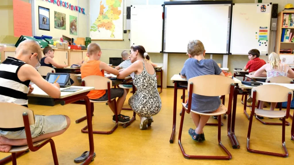 professora auxiliando aluno durante a aula